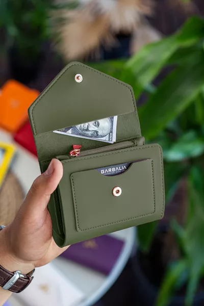 محفظة نسائية صغيرة باللون الأخضر الزيتي، مصنوعة من الجلد النباتي، بها فتحة للعملات المعدنية وعدة أماكن للبطاقات