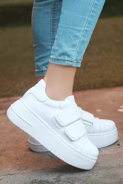 حذاء رياضي أبيض بين النعل الفيلكرو