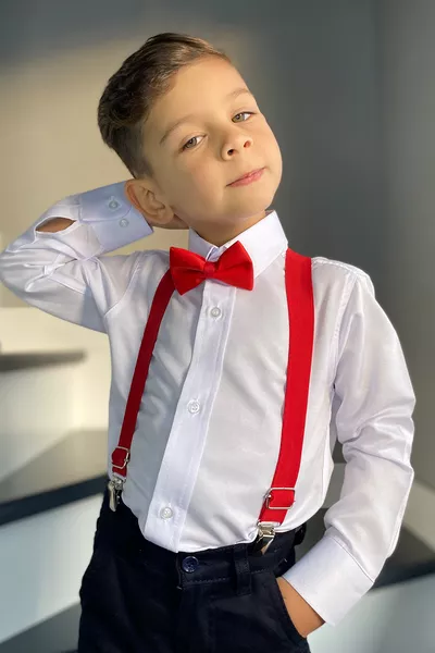 Completo da bambino maschio con camicia bianca a maniche lunghe, bretelle e papillon