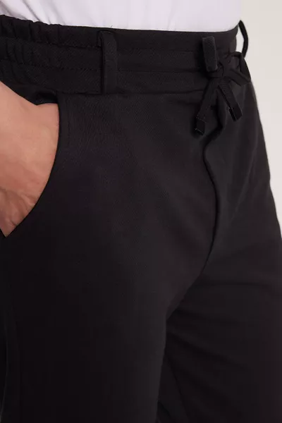 بنطال رجالي أسود رياضي بقصة ضيقة من القطن، مزود بحزام للخصر، جيوب جانبية، وحواف قابلة للطي