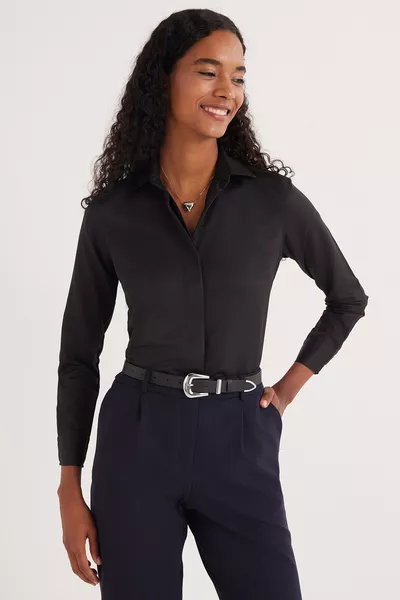 قميص نسائي أسود أساسي بأكمام طويلة، بقصة ضيقة تناسب الجسم، مع أزرار مخفية