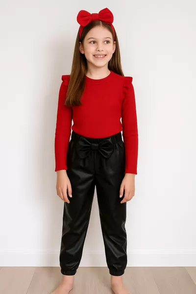 ملابس فتاة: بنطال بتفاصيل ربطة من الجلد الأسود، وبلوزة حمراء بكشكشة على الكتف، وطقم رباط شعر.