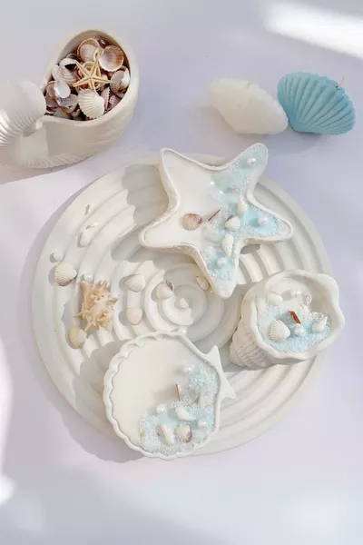 Ensemble de coquillages et perles poudrées avec bougie sur plateau rond
